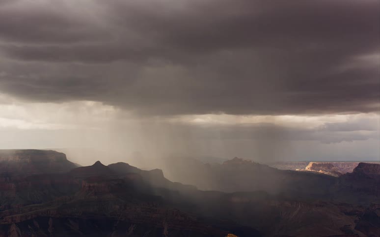 Clouds above a mountain range pour rain
