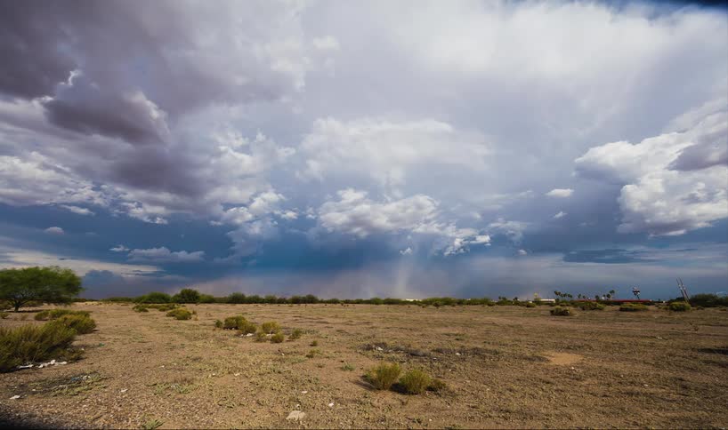 A field has heavy clouds in the skyline