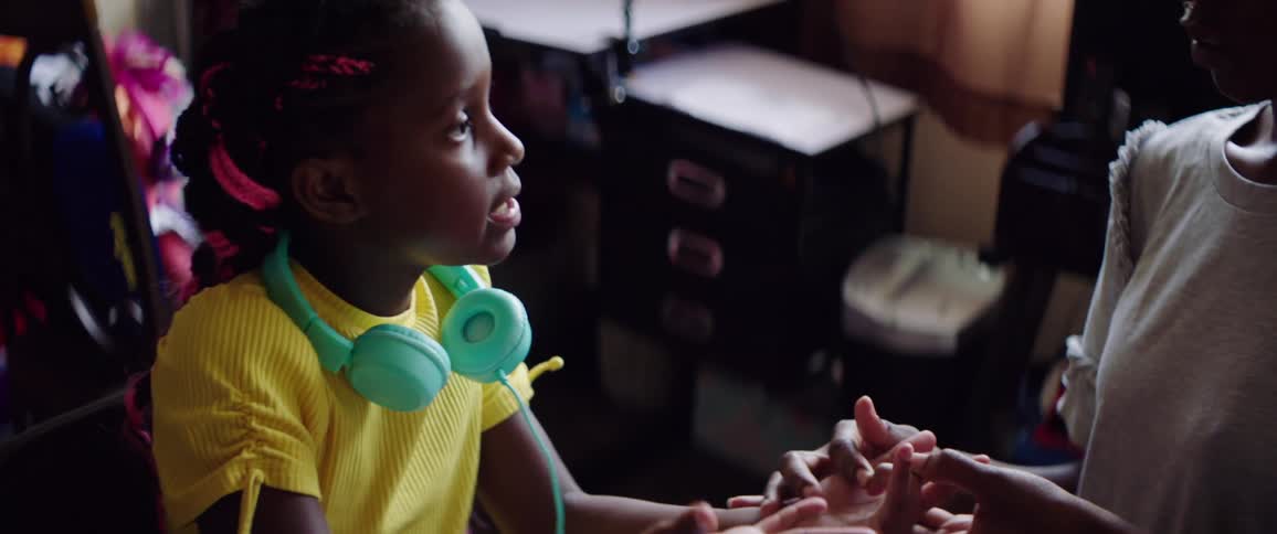 A woman teaching a little girl with a headphones math