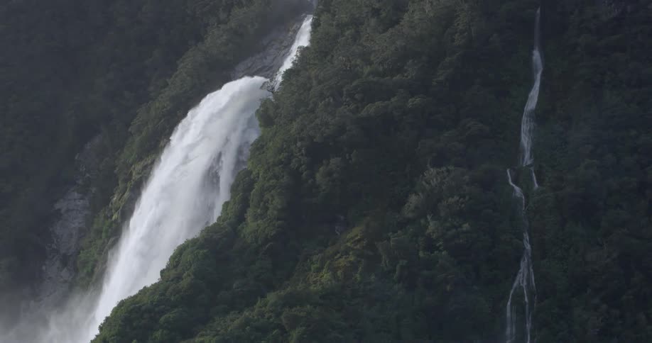 A tree covered mountain has a large waterfall