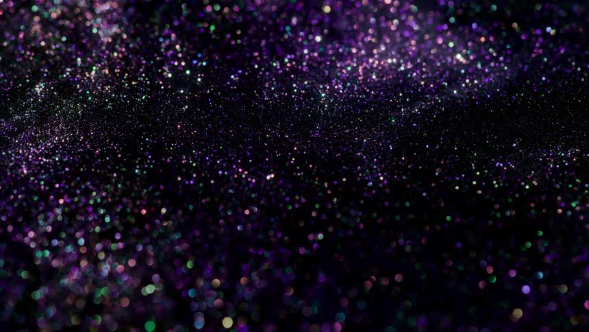 Colorful specks of shimmering glitter floating over a black background
