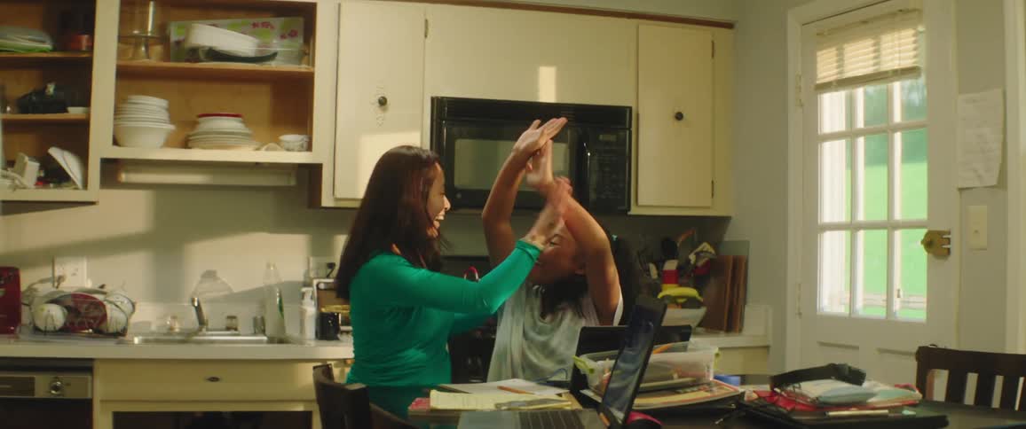 Teacher celebrates with student over homework during a homeschooling session in the kitchen