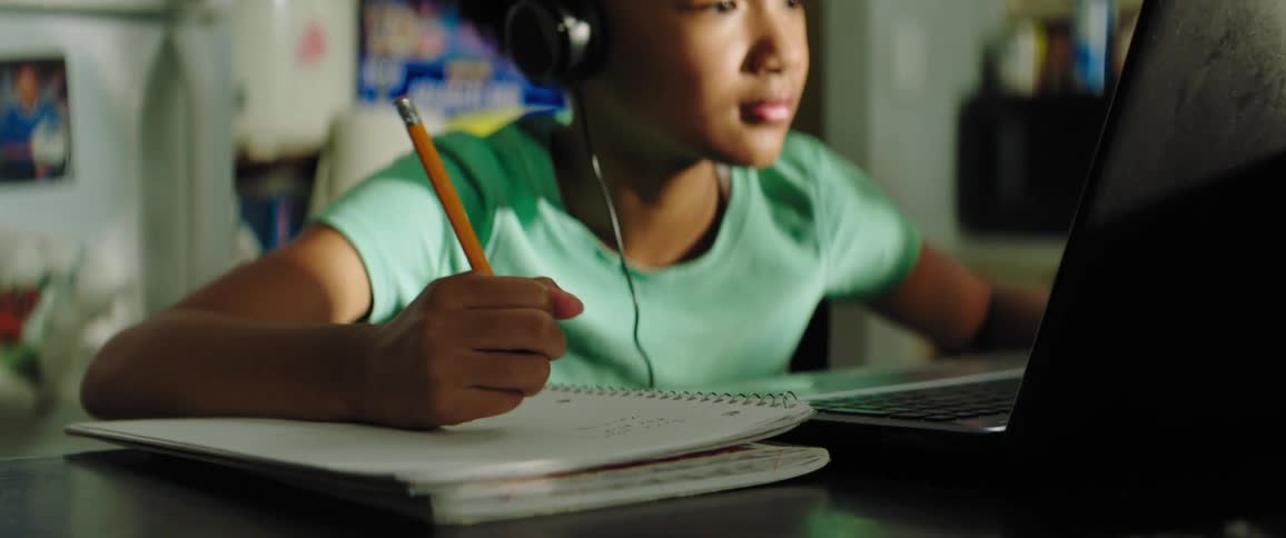 Young girl distance learning on lap top from kitchen table