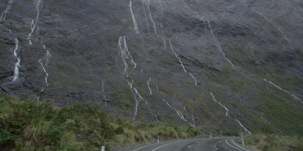 Small streams running down a mountainside as seen from a road
