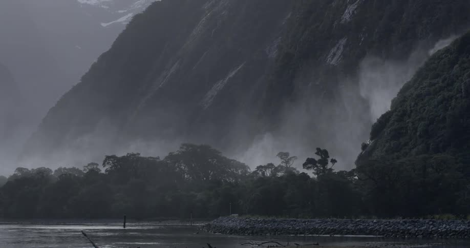 Mist rising from behind trees at the foot of the mountain