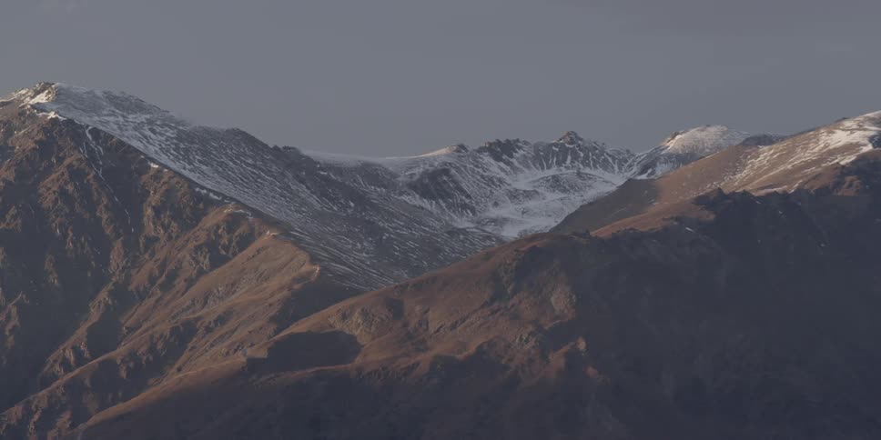 A mountain range has some snow on it