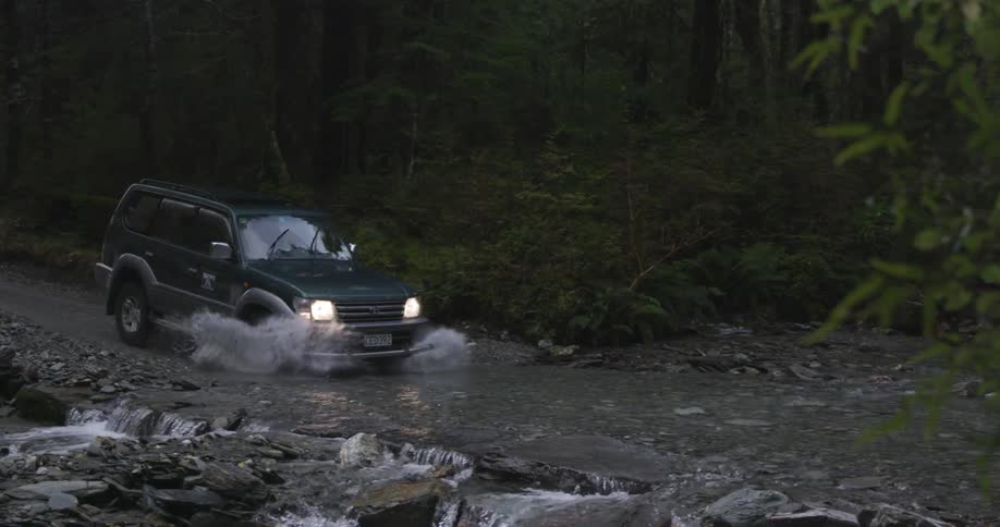 A vehicle drives through a stream