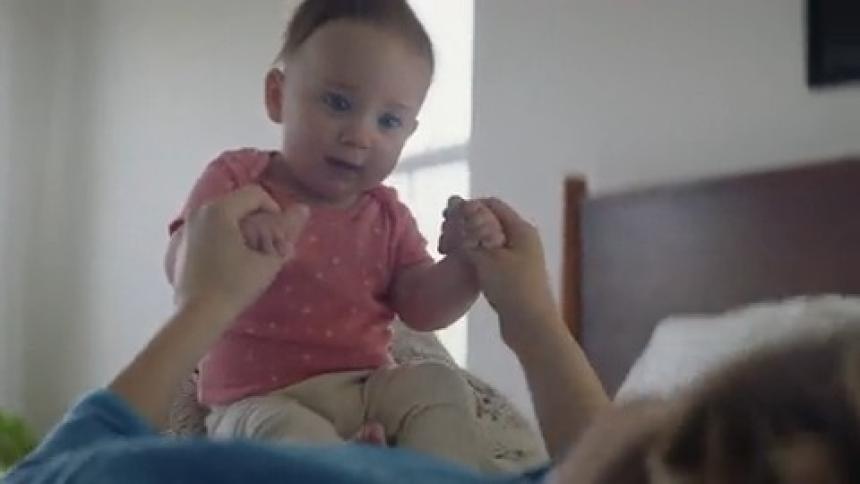 Close up of a mother lying in bed playing with her toddler