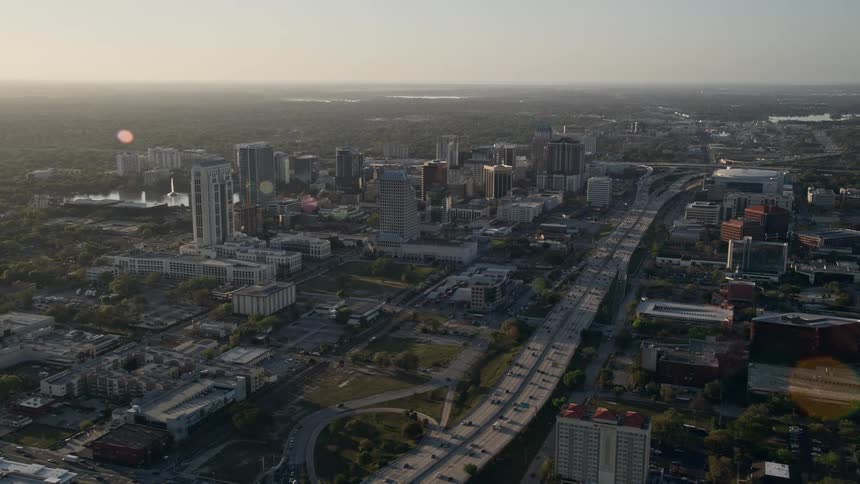 Aerial footage of morning traffic running through Downtown Orlando and Interstate 4 at sunrise with office buildings industries and transportation visible in the background in Florida