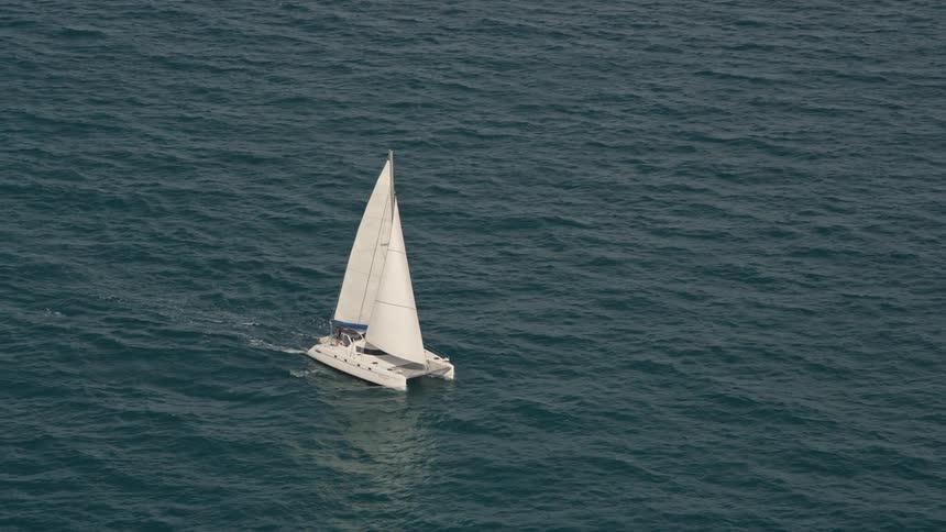 Aerial footage of a white catamaran sailing on the blue Atlantic Ocean near South Beach FL