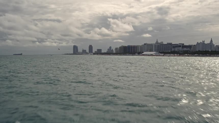 A stunning aerial view of Miami Beach Florida captures a breathtaking sight of oceanfront hotels and condos as the camera tilts up from the ocean