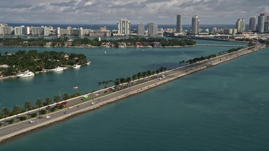 Aerial footage of the MacArthur Causeway with light traffic reveals South Beach in Florida as cars travel along the highway bordered by water