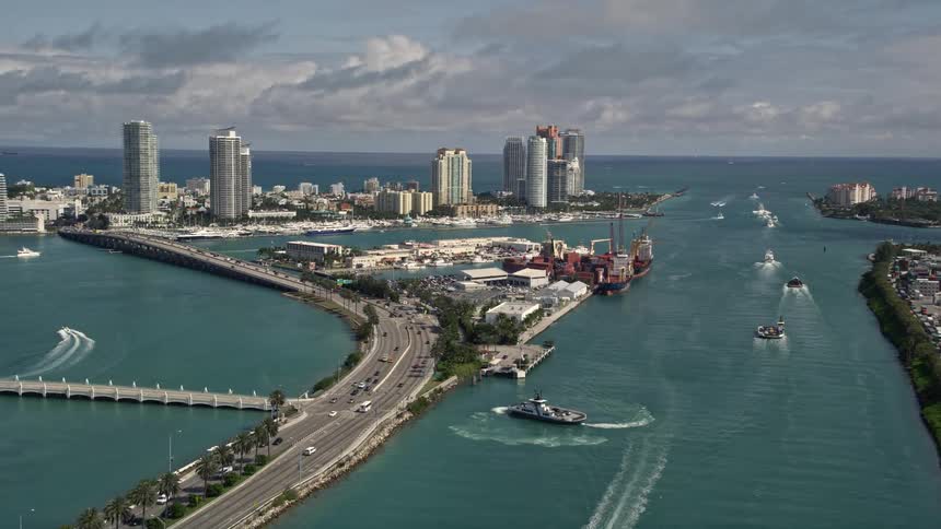 Aerial footage of ferries approaching the Government Cut harbor panning left to reveal the skyscrapers and coastline of South Beach Miami