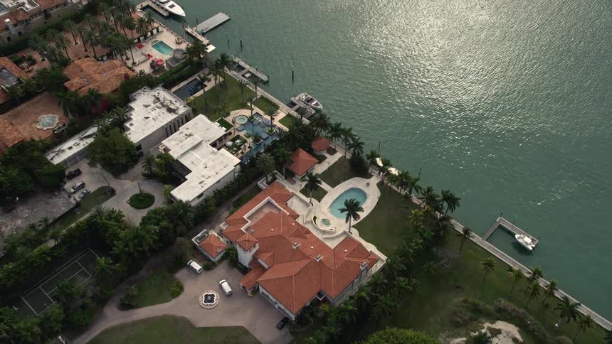 Approaching a luxurious waterfront mansion this aerial clip of Star Island Florida tilts to a stunning birds eye view of the upscale homes and isles
