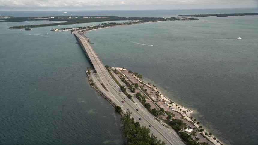Aerial footage pans across the Rickenbacker Causeway in Miami Florida showcasing the scenic view of the ocean and natural landscape surrounding the bridge