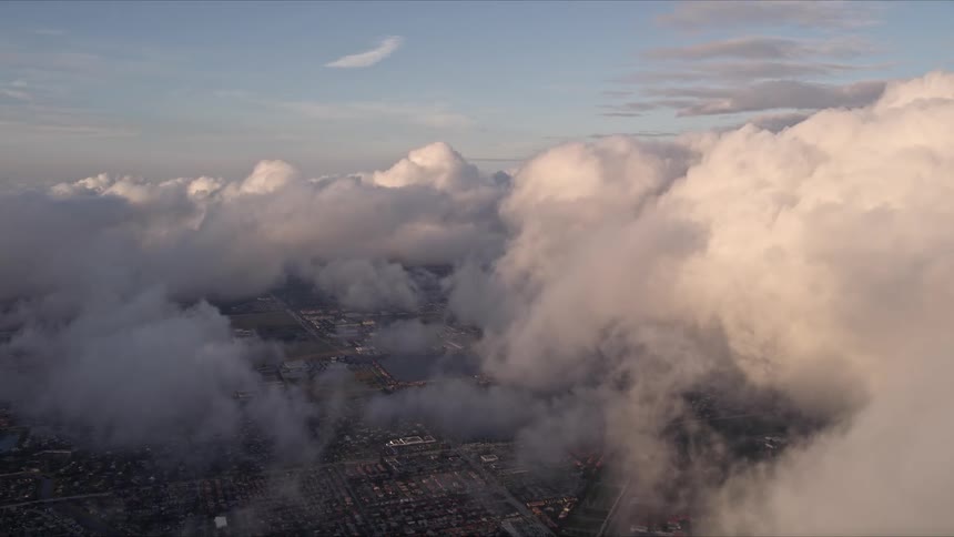 Aerial view of cloudy skies at sunset panning left over Miami Floridas eastern and southern coasts