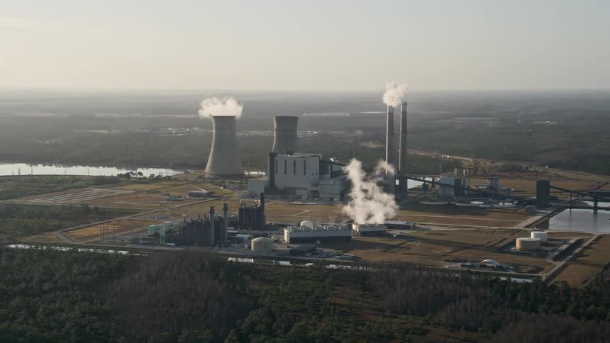 Aerial footage of the Stanton Energy Center power plant in Florida at sunrise with smoke stacks emitting fumes