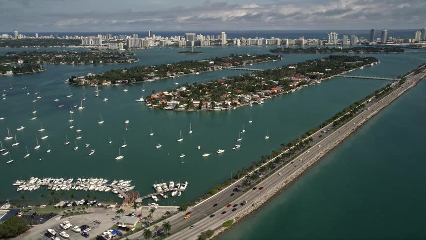 Aerial footage of the MacArthur Causeway passing by sailboats on Biscayne Bay and the Palm and Hibiscus Islands in Miami Florida