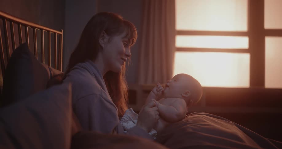 A mother holds her baby in her lap and sings to it