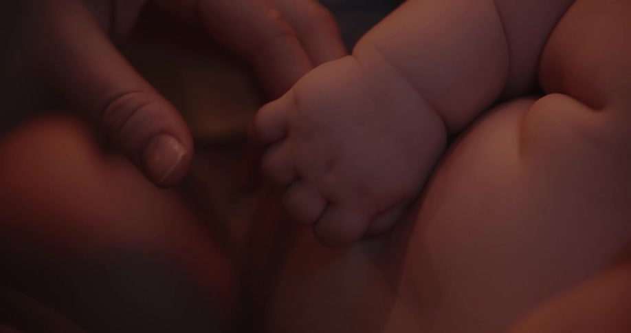 A baby grabs its mothers fingers