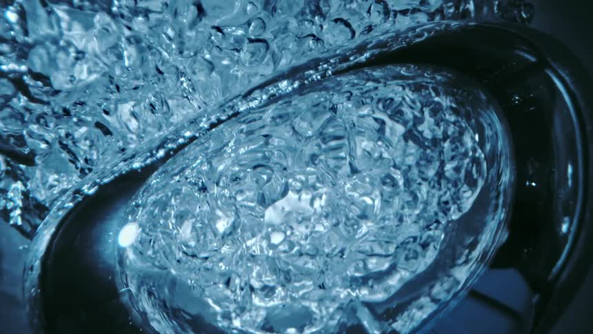 Light shines on clear water as it ripples and moves and bubbles float and shrink and moisture remains on the surface