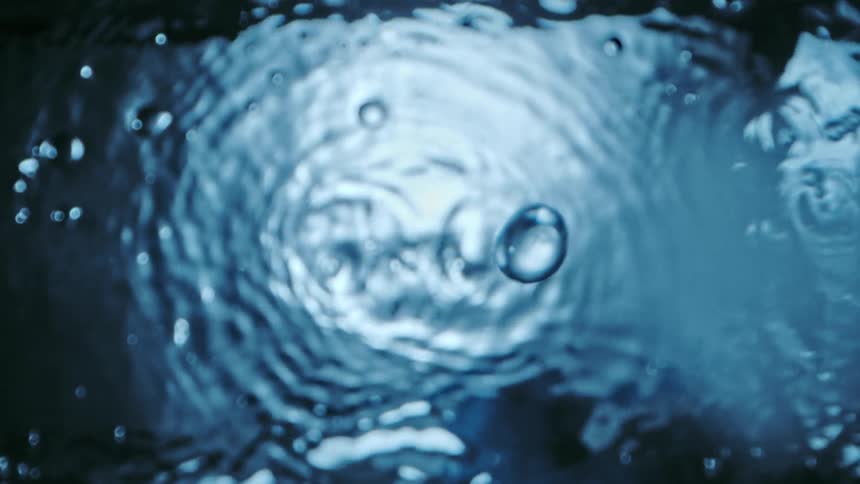 Water dripping down and splashing into more water creating ripples on the surface