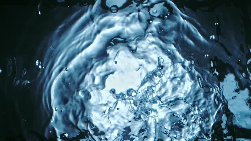 Water being poured into a puddle of water creating ripples on the surface