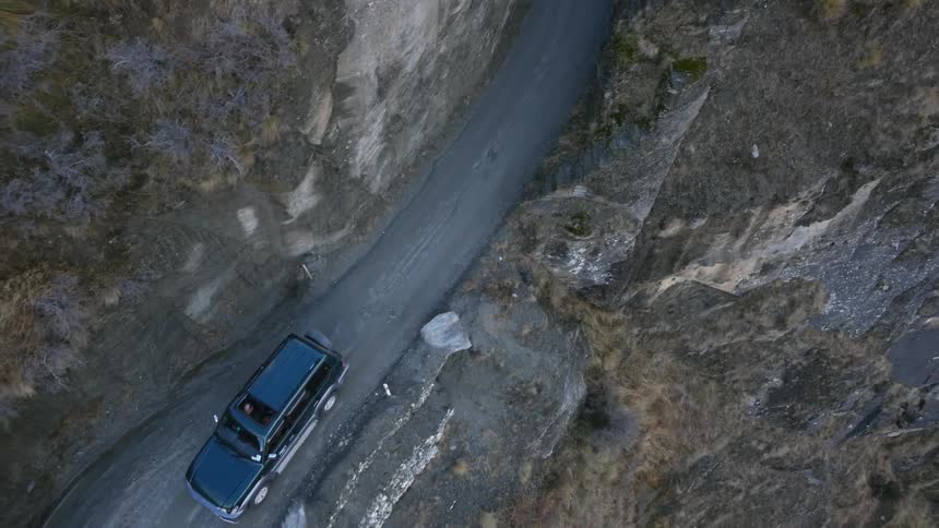 A black suv drives down a winding road
