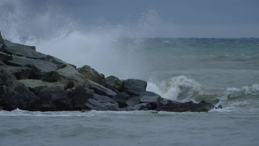 Water waves are crashing against the rocky coast