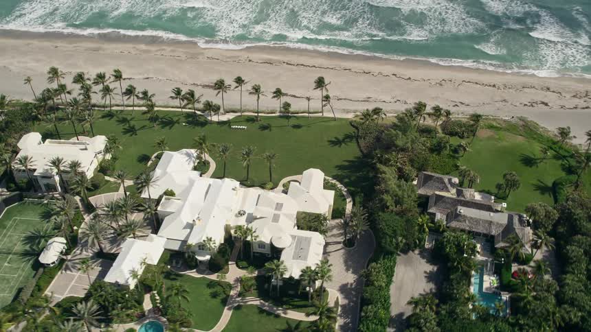 An aerial view of a luxurious mansion with a pool nestled on the beachfront of Hobe Sound in Florida
