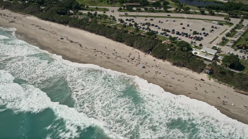 Sunbathers enjoying the waves at a Jupiter beach in Florida as seen from an aerial perspective