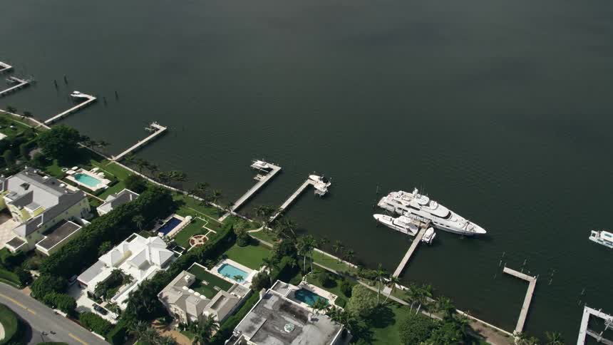 Aerial footage of a luxurious waterfront property in Palm Beach Florida with a large yacht docked on the lake