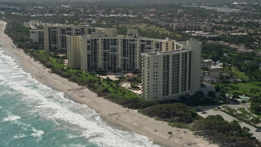 Approaching large beachfront condominium buildings in Jupiter Florida from an aerial 