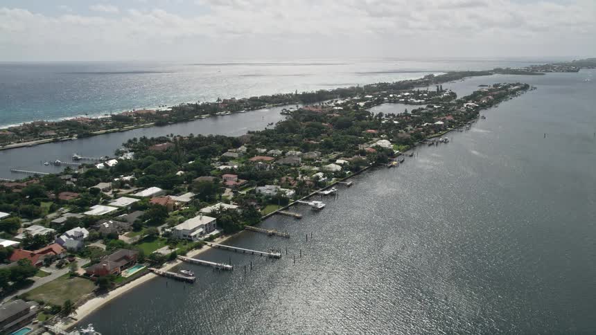 Aerial footage of lakefront mansions with docks and boats on an island in Manalapan Florida