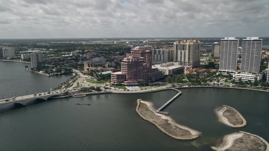 Aerial footage of an approach to a modern commercial property located along the lakefront of West Palm Beach Florida