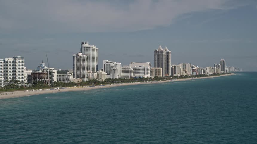 A stunning aerial view of hotels and high-rise buildings along Miami Beachs shoreline bustling with beachgoers enjoying the sunshine and recreation
