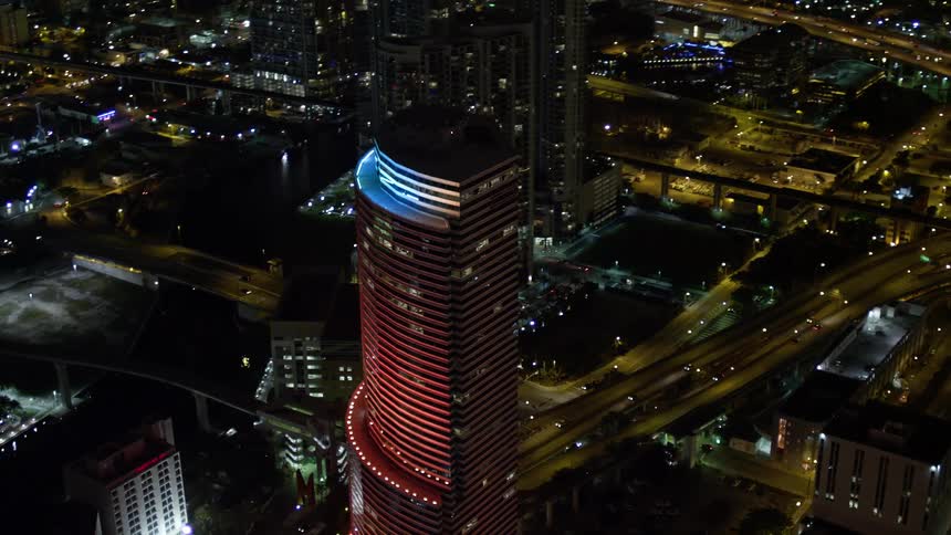 A stunning aerial shot of Miami Tower at night showcasing its colorful lights in the heart of Downtown Miami