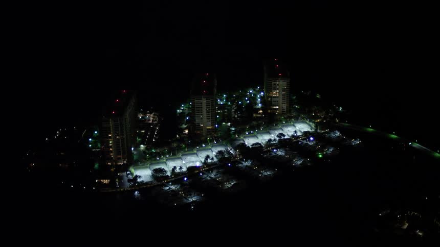 A stunning aerial view of waterfront condominium complexes on Grove Isle Florida at night