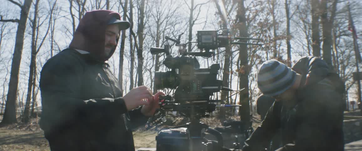 Man adjusts camera equipment outside on a sunny day