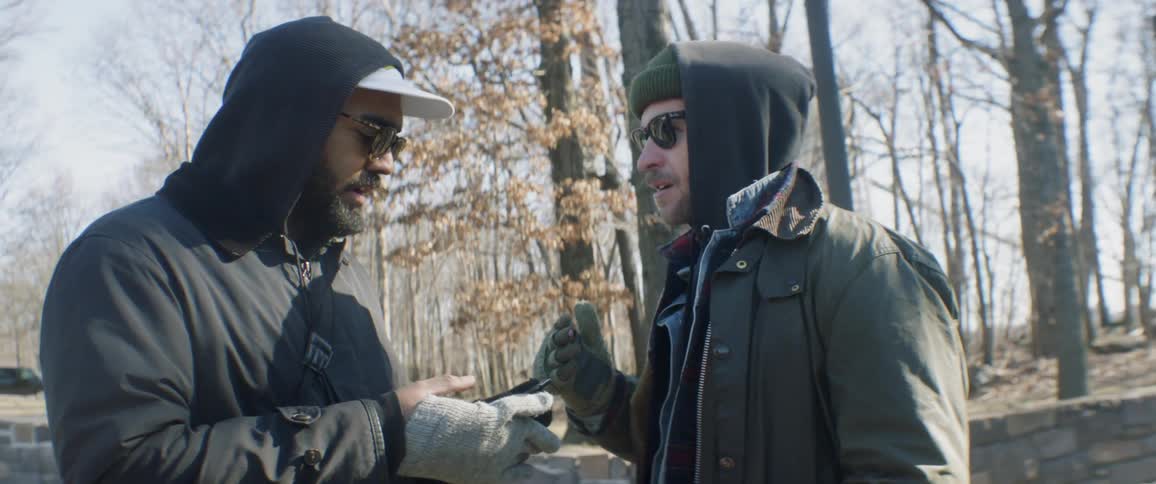 Two men look at a phone outside