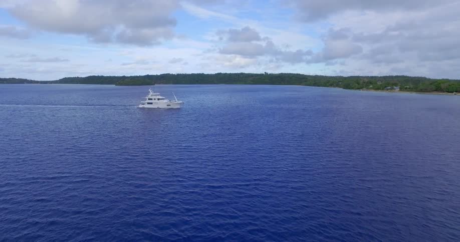 A boat travels across a lake on a partly cloudy day