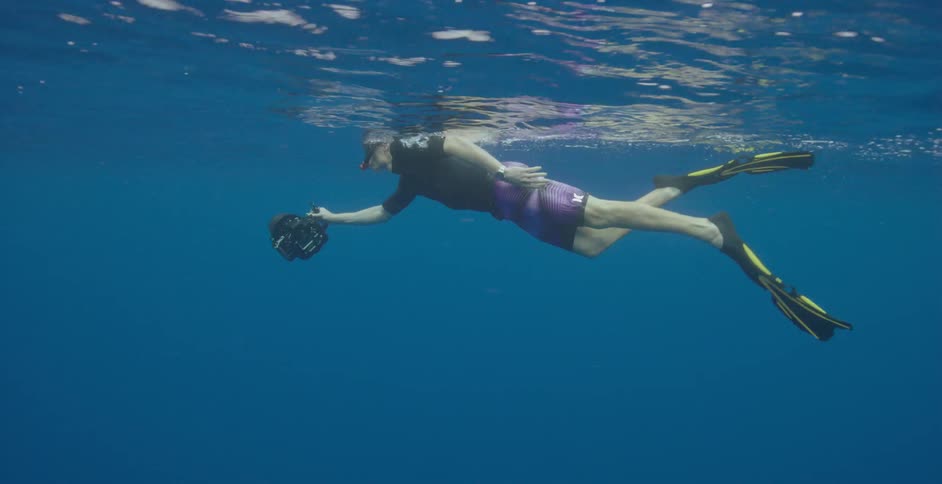 A man is swimming with a camera underwater