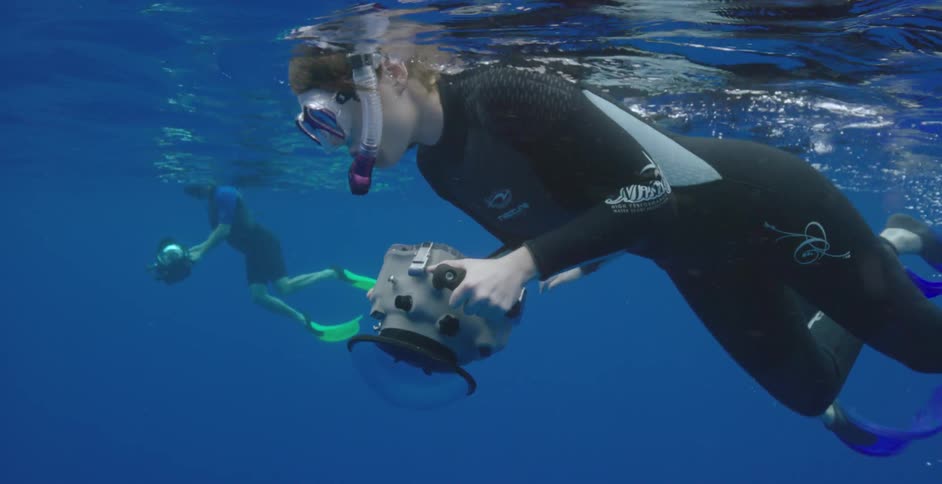Two people snorkeling and holding cameras underwater