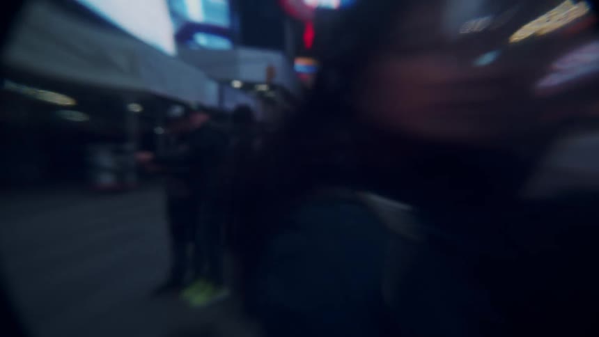 A crowd walks through a tourist part of downtown at night