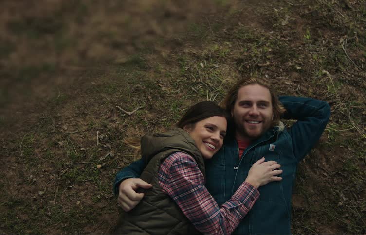 A couple embracing and talking while lying on mossy ground