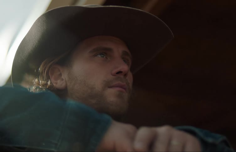 A man in a cowboy hat ponders