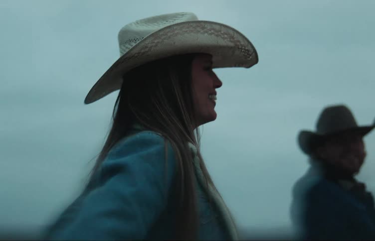 Friends wearing cowboy hats walk outdoors with setting sun on the horizon