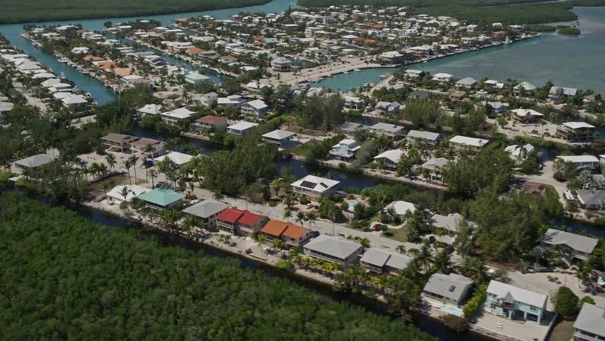 Approaching aerial view of homes on canals along the sunny shores of Islamorada Florida