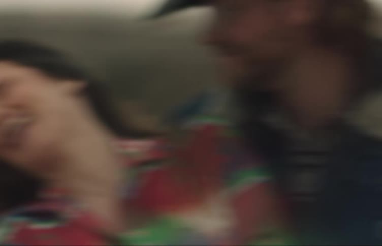 A couple laugh while dancing in a field