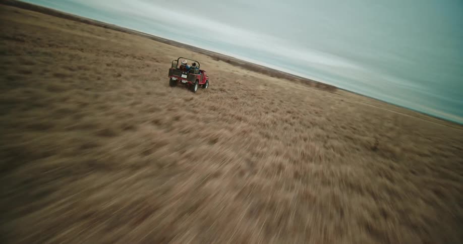 Aerial view of red jeep driving in the field